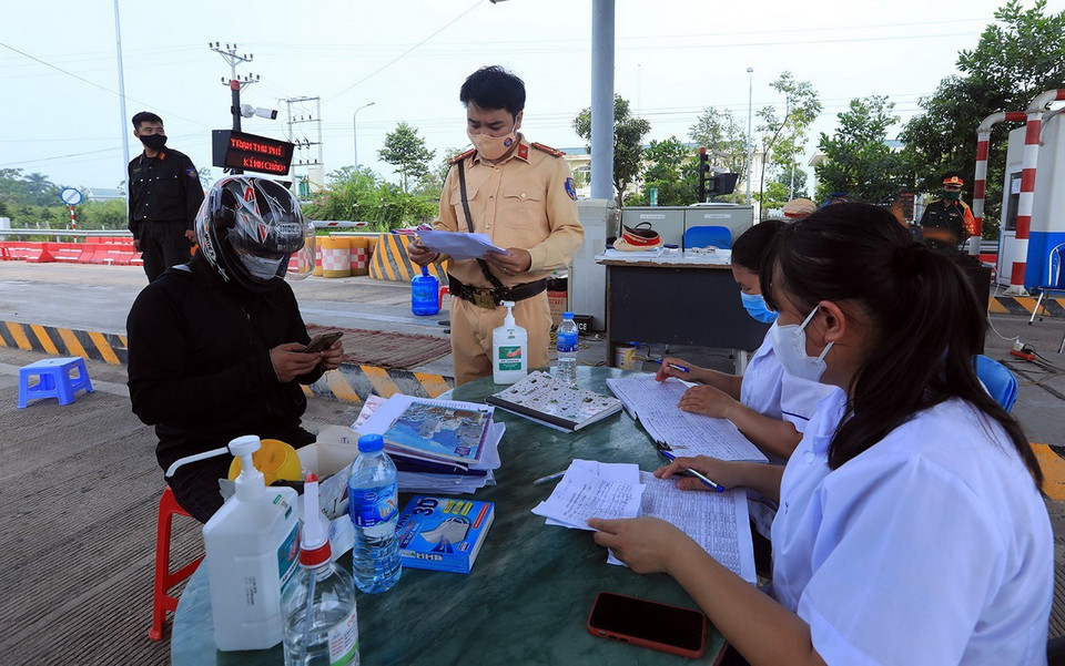  Anh Nguyễn Tiến Thành (áo đen, thường trú tại thành phố Việt Trì, tỉnh Phú Thọ) khai báo y tế và xuất trình giấy thông hành tại chốt kiểm dịch đầu cầu Văn Lang, huyện Ba Vì. (Ảnh: Tuấn Anh/TTXVN)
