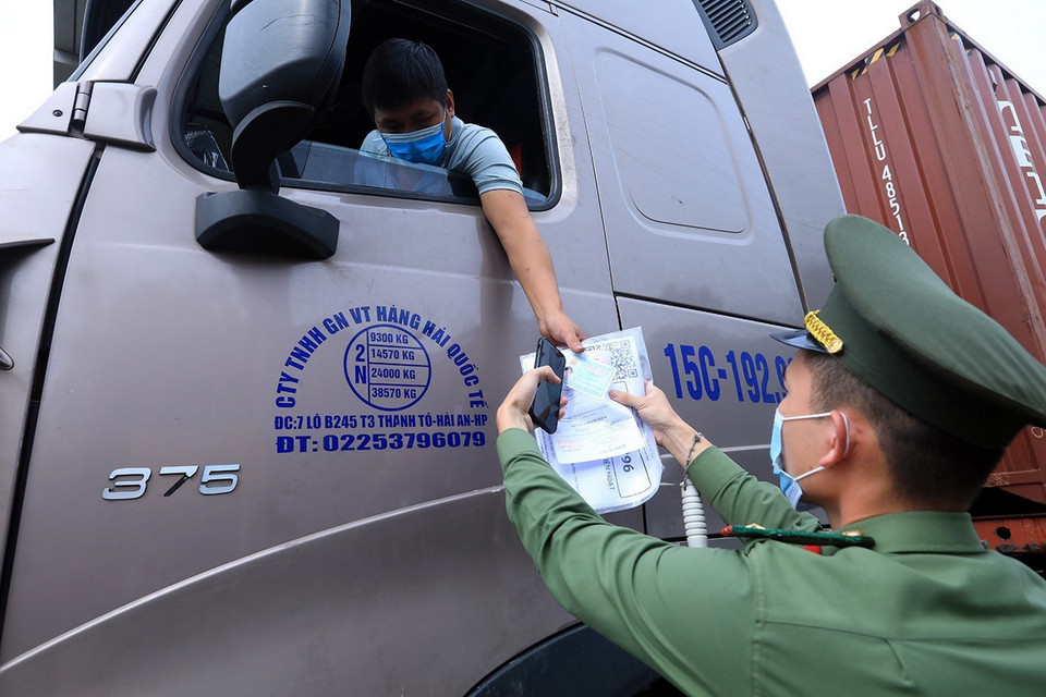  Lực lượng chức năng tại chốt kiểm dịch đầu cầu Trung Hà, huyện Ba Vì, kiểm tra giấy thông hành và thẻ “luồng xanh” của các phương tiện vận tải ra, vào thành phố. (Ảnh: Tuấn Anh/TTXVN)