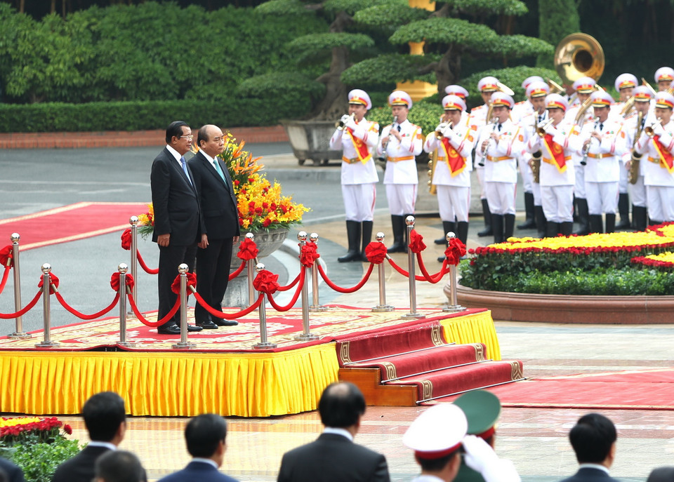 Thủ tướng Nguyễn Xuân Phúc và Thủ tướng Campuchia Samdech Techo Hun Sen trên bục danh dự, thực hiện nghi lễ chào cờ. (Ảnh: Văn Điệp/TTXVN)