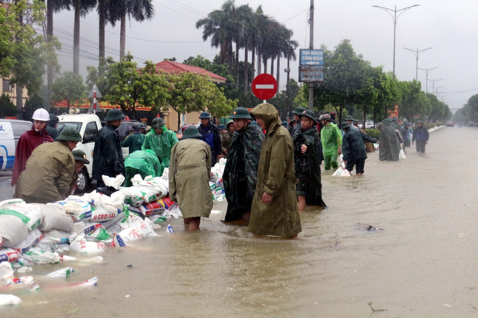 Lực lượng chức năng và người dân đắp đê cát để chống nước lũ tràn vào khu dân cư. (Ảnh: Đại Nghĩa/TTXVN)