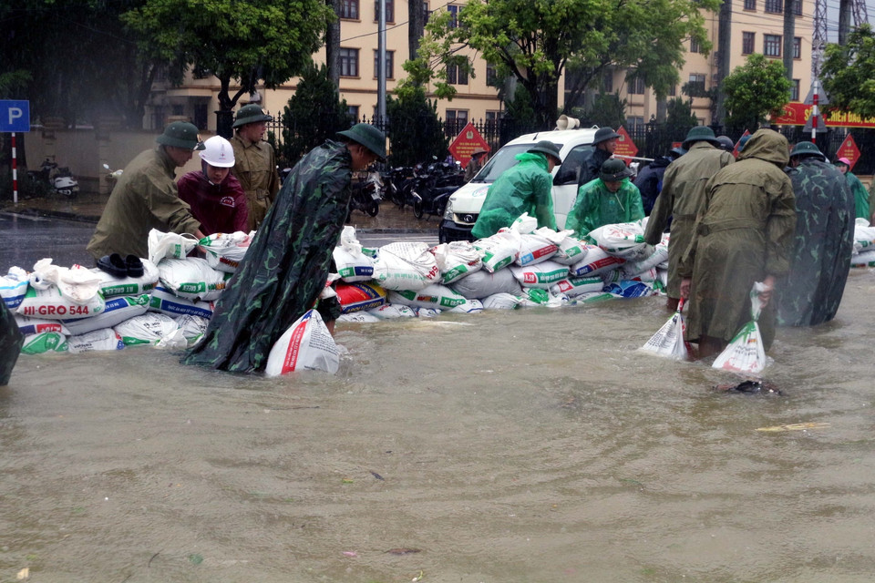 Lực lượng chức năng và người dân đắp đê cát để chống nước lũ tràn vào khu dân cư. (Ảnh: Đại Nghĩa/TTXVN)