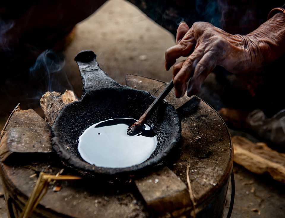 Sáp ong được đun trên bếp than dùng để vẽ lên vải lanh. (Ảnh: Nam Thái/TTXVN)