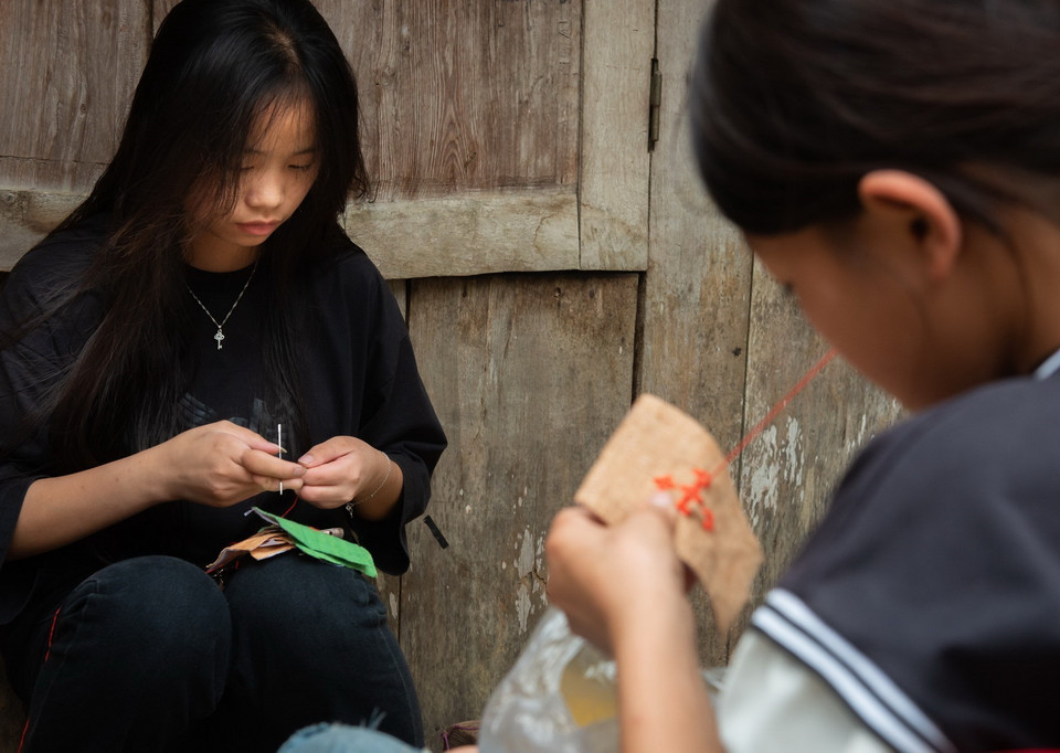  Các em gái dân tộc Mông học thêu đắp vải màu. (Ảnh: Nam Thái/TTXVN)