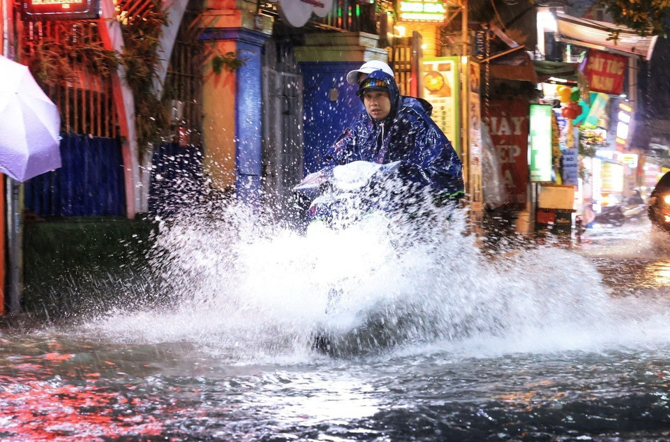 Người dân đi lại khó khăn khi trời mưa to tại phố Bùi Xương Trạch, quận Thanh Xuân. (Ảnh: Tuấn Anh/TTXVN)