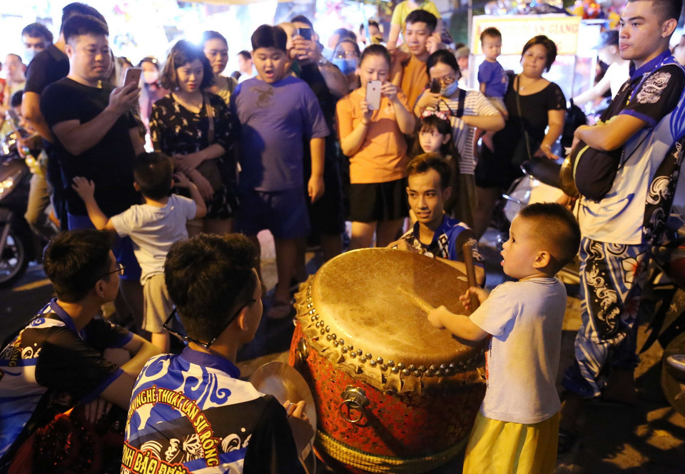 Đám đông thích thú với màn biểu diễn ngẫu hứng của một em bé. (Ảnh: Hoàng Hiếu/TTXVN)