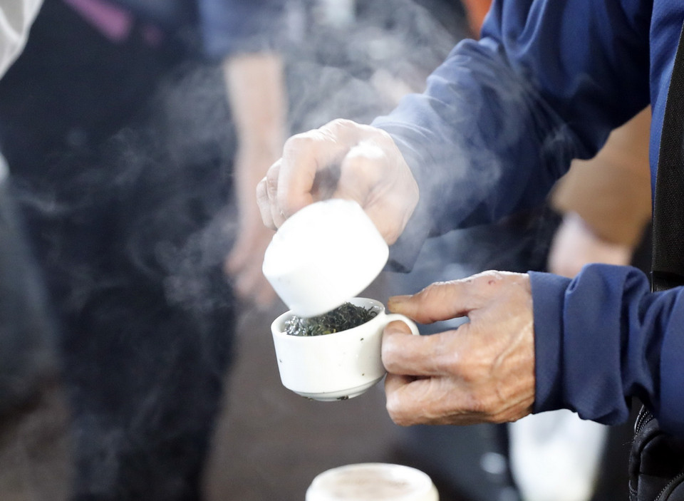  Sau khi pha chè được vài phút người mua đảo đi đảo lại chè qua hai chén để thử sắc của nước chè. (Ảnh: Trần Việt/TTXVN)