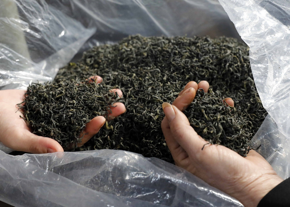  Người mua thử chè bằng cách cảm nhận độ khô của chè. (Ảnh: Trần Việt/TTXVN)