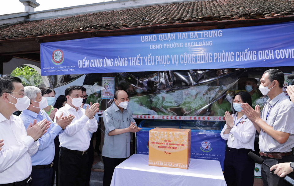 Chủ tịch nước Nguyễn Xuân Phúc tặng quà điểm cung ứng hàng thiết yếu phục vụ nhân dân tại phường Bạch Đằng, quận Hai Bà Trưng, Hà Nội. (Ảnh: Thống Nhất/TTXVN) 