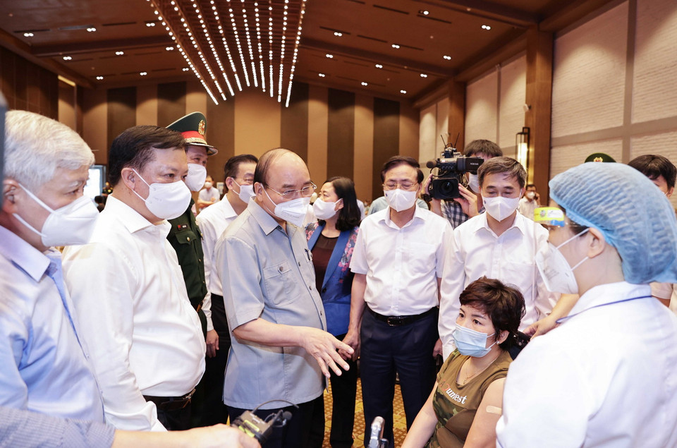 Chủ tịch nước Nguyễn Xuân Phúc thăm hỏi, động viên các nhân viên y tế làm nhiệm vụ tiêm vaccine phòng COVID – 19 cho nhân dân tại phường Bạch Đằng, quận Hai Bà Trưng, Hà Nội. (Ảnh: Thống Nhất/TTXVN) 