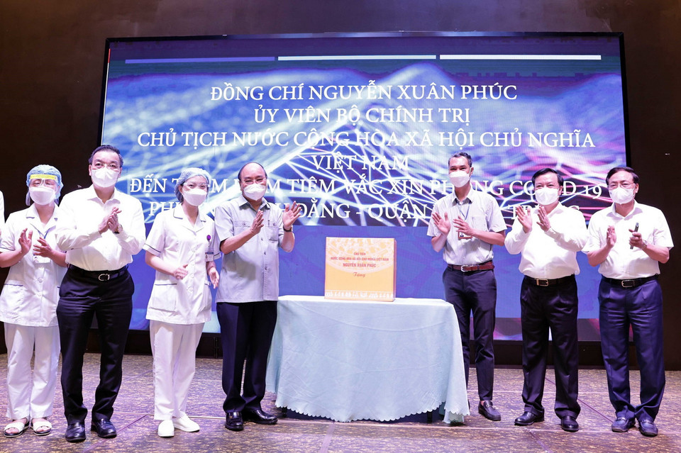 Chủ tịch nước Nguyễn Xuân Phúc thăm hỏi, động viên các nhân viên y tế làm nhiệm vụ tiêm vaccine phòng COVID – 19 cho nhân dân tại phường Bạch Đằng, quận Hai Bà Trưng, Hà Nội. (Ảnh: Thống Nhất/TTXVN) 