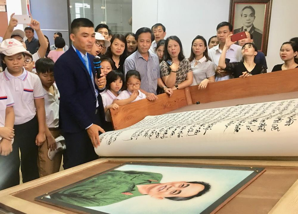 Kỷ lục gia, nghệ nhân thư pháp Võ Dương giới thiệu từng trang sách thư pháp đến với người xem. (Ảnh: Võ Dung/TTXVN)