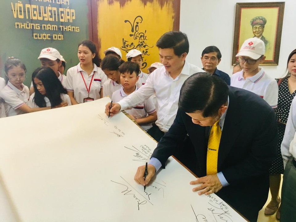 Các đại biểu ký tên kỷ niệm trên sách thư pháp viết về Đại tướng Võ Nguyên Giáp. (Ảnh: Võ Dung/TTXVN)