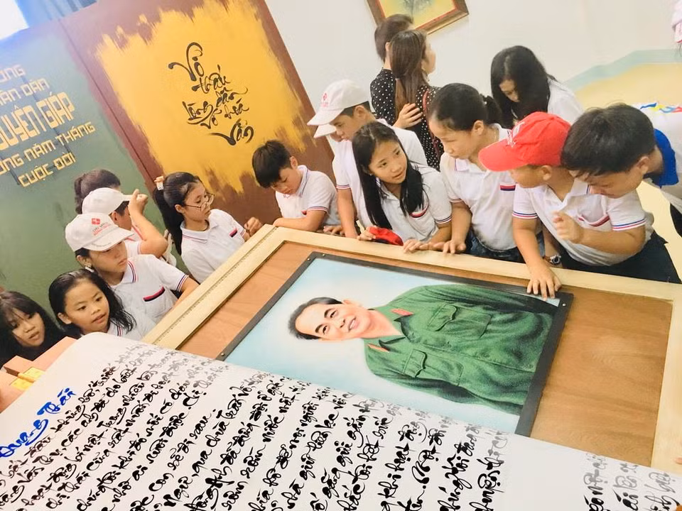 Các em học sinh hào hứng tham quan quyển sách thư pháp viết về Đại tướng Võ Nguyên Giáp. (Ảnh: Võ Dung/TTXVN)