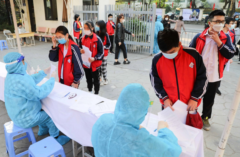 Nhân viên y tế kiểm tra thông tin, hướng dẫn học sinh làm các thủ tục tại điểm tiêm Trường THCS Khương Đình, quận Thanh Xuân. (Ảnh: Thanh Tùng/TTXVN)