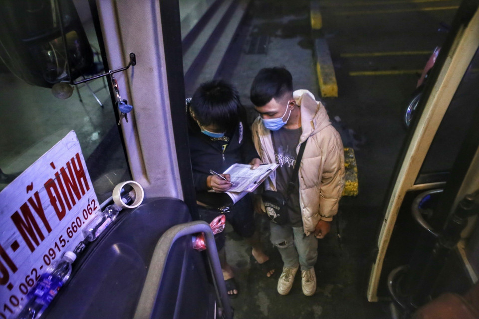 Phụ xe kiểm tra thông tin từng hành khách trước khi lên xe. (Ảnh: Tuấn Đức/TTXVN)