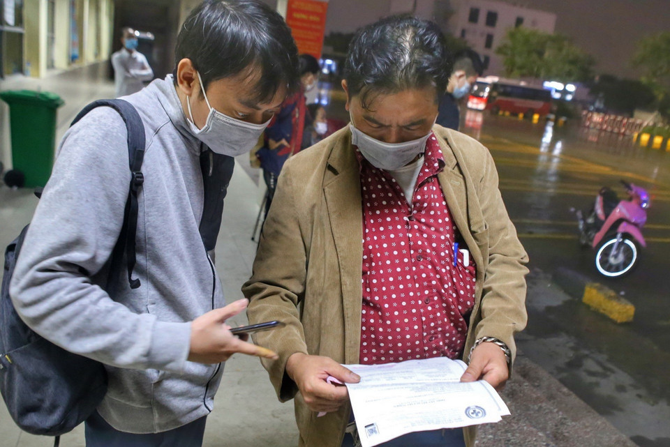 Lái xe Trần Tuấn Anh kiểm tra giấy tờ xét nghiệm PCR của hành khách. (Ảnh: Tuấn Đức/TTXVN)