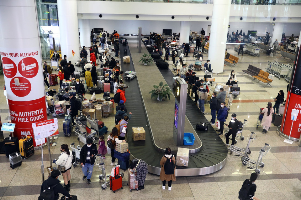 Cảng Hàng không Nội Bài những ngày này phải tăng cường thêm 20% nhân viên trực để kịp thời phục vụ tốt cho hành khách về quê đón Tết. Bên trong khu vực lấy hành lý đông đúc, khiến việc di chuyển ra ngoài sảnh lâu hơn thường lệ. (Ảnh: Huy Hùng/TTXVN)