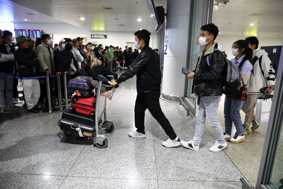 Hành khách từ nước ngoài trở về đang tìm người thân trong "biển" người đến đón. (Ảnh: Huy Hùng/TTXVN)