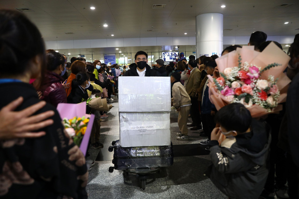 Người dân với những bó hoa cầm tay chờ đón người thân sau 2 năm đại dịch COVID-19 giờ mới trở về nhà. (Ảnh: Huy Hùng/TTXVN)