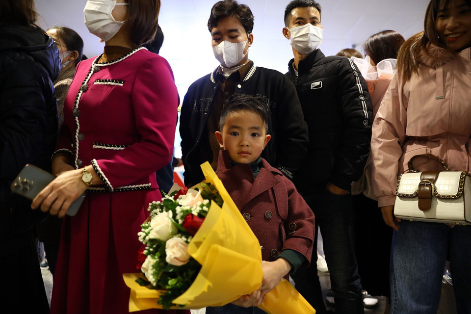 Một em nhỏ cầm hoa đợi bố trở về sau nhiều năm làm việc tại Hàn Quốc. (Ảnh: Huy Hùng/TTXVN)