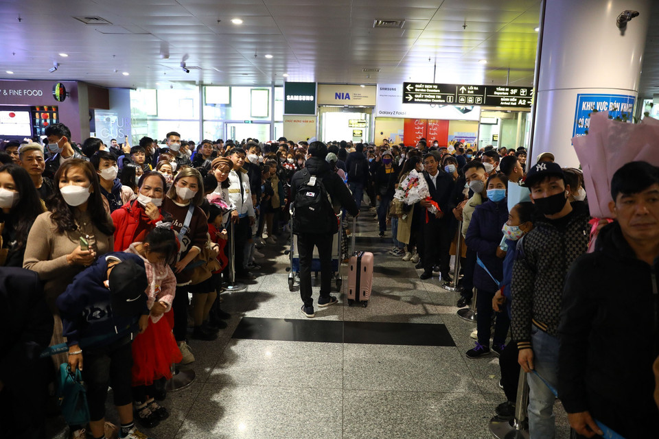 Hàng trăm người đứng chật kín tại khu vực cửa đón khách A1 đợi người thân từ nước ngoài trở về. (Ảnh: Huy Hùng/TTXVN)