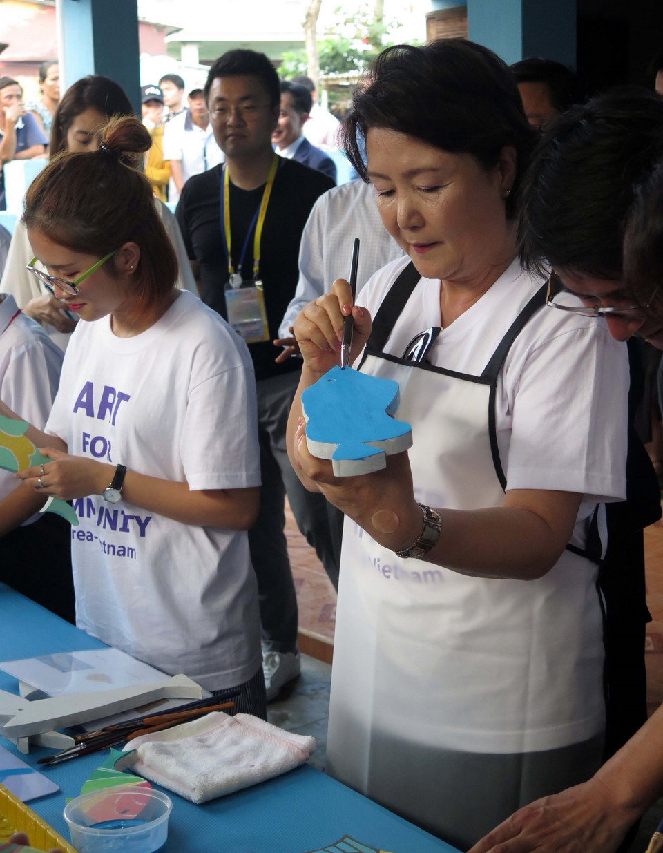 Phu nhân Kim Jung Sook tô màu trên cá gỗ tại Làng bích họa Tam Thanh. (Ảnh: Đỗ Trưởng/TTXVN)