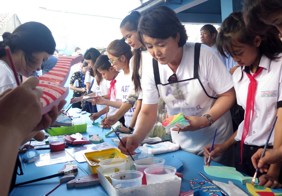 Phu nhân Kim Jung Sook tô màu trên cá gỗ tại Làng bích họa Tam Thanh. (Ảnh: Đỗ Trưởng/TTXVN)
