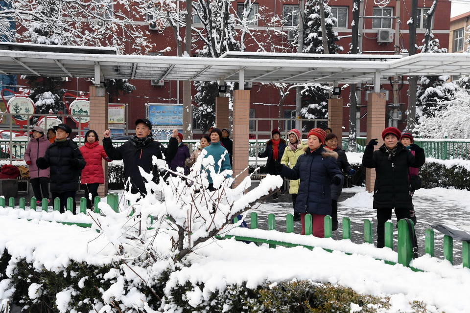 Người dân tập thể dục trong công viên phủ trắng tuyết tại Bắc Kinh, Trung Quốc. (Ảnh: THX/TTXVN)