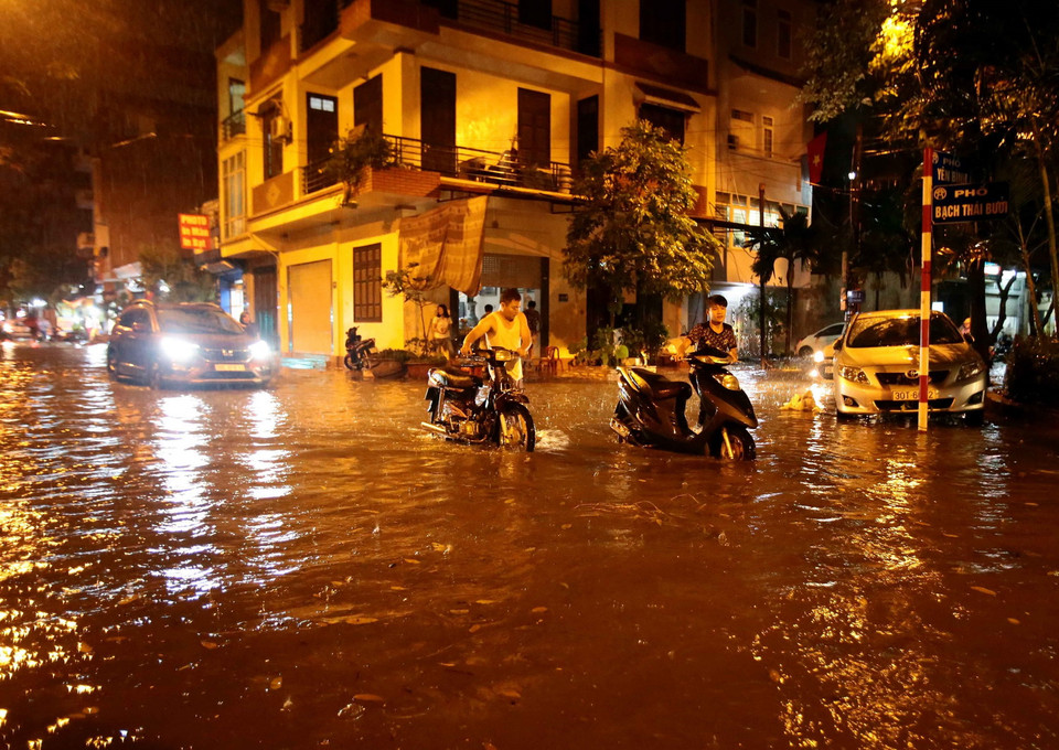 Người dân phải dắt xe qua điểm ngập sâu tại đường Bạch Thái Bưởi, Khu đô thị Văn Quán, quận Hà Đông. (Ảnh: Phạm Kiên/TTXVN)