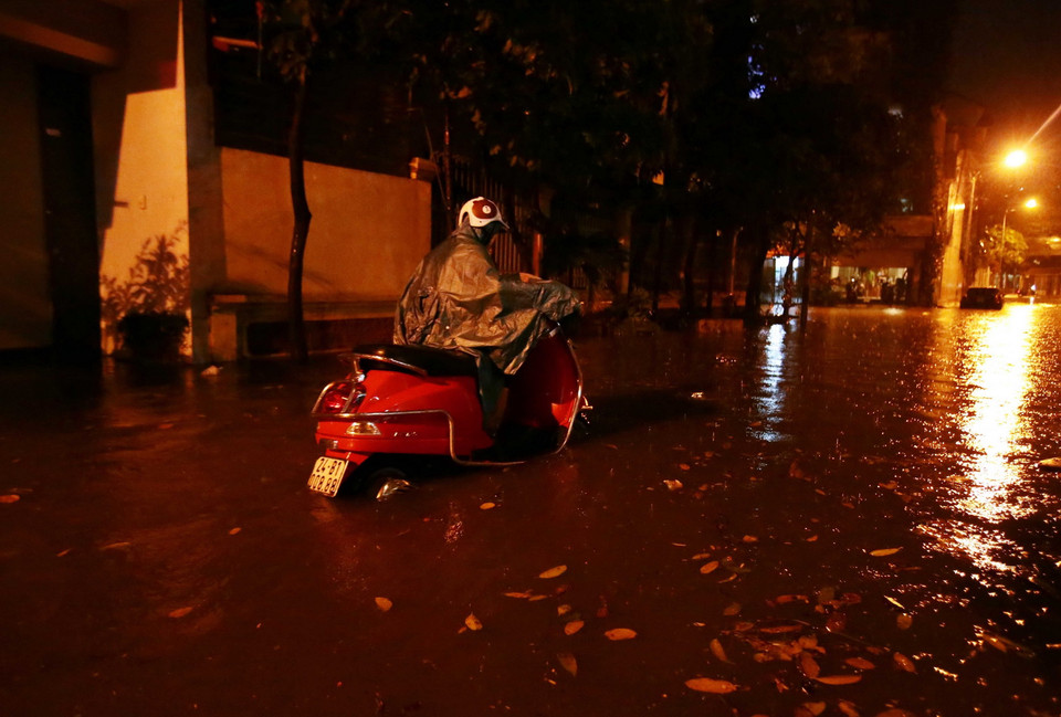 Người dân phải chọn cách dắt xe để đi qua những điểm ngập sâu tại Khu đô thị Văn Quán, quận Hà Đông. (Ảnh: Phạm Kiên/TTXVN)