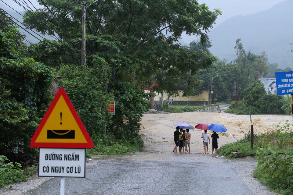 Mặc dù đã có biển cảnh báo lũ, nhiều người dân vẫn ra sát mép nước để xem lũ về tại ngầm Mỏ Chảo, thị trấn Đồng Mỏ, huyện Chi Lăng, Lạng Sơn. (Ảnh: Phạm Hậu/TTXVN)