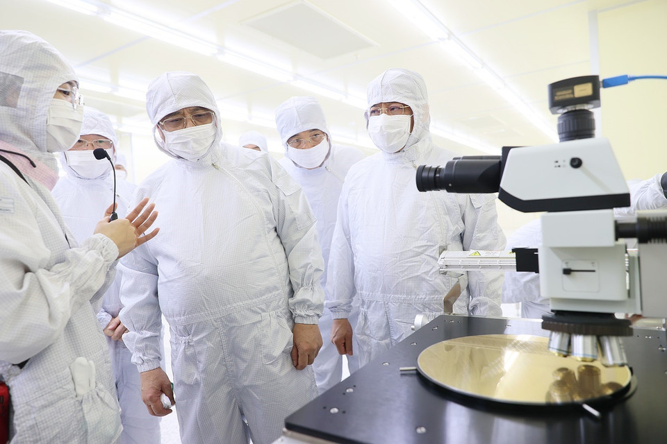 Thủ tướng Phạm Minh Chính nghe giới thiệu về dây chuyền sản xuất chip bán dẫn của Công ty TNHH Hana Micro Vina. (Ảnh: Dương Giang-/TXVN)
