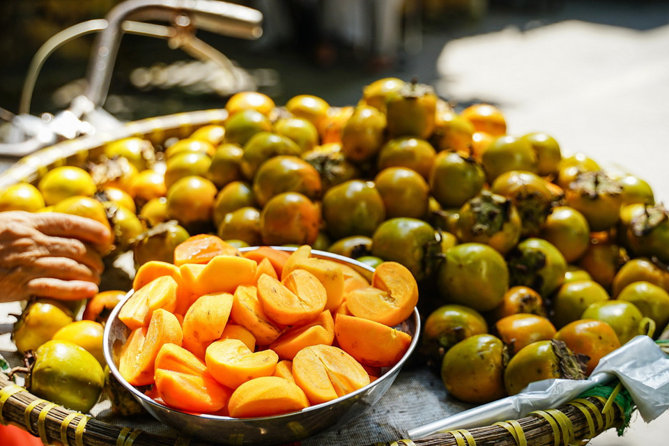 Hồng ngâm có dạng quả nhỏ, vỏ xanh pha vàng, khi vừa hái xuống không thể ăn được ngay mà phải ngâm nước vài ngày để khử chát và để hồng lên bột, lúc này quả hồng trở nên giòn hơn, ngọt hơn. (Ảnh: Khánh Hòa/TTXVN)