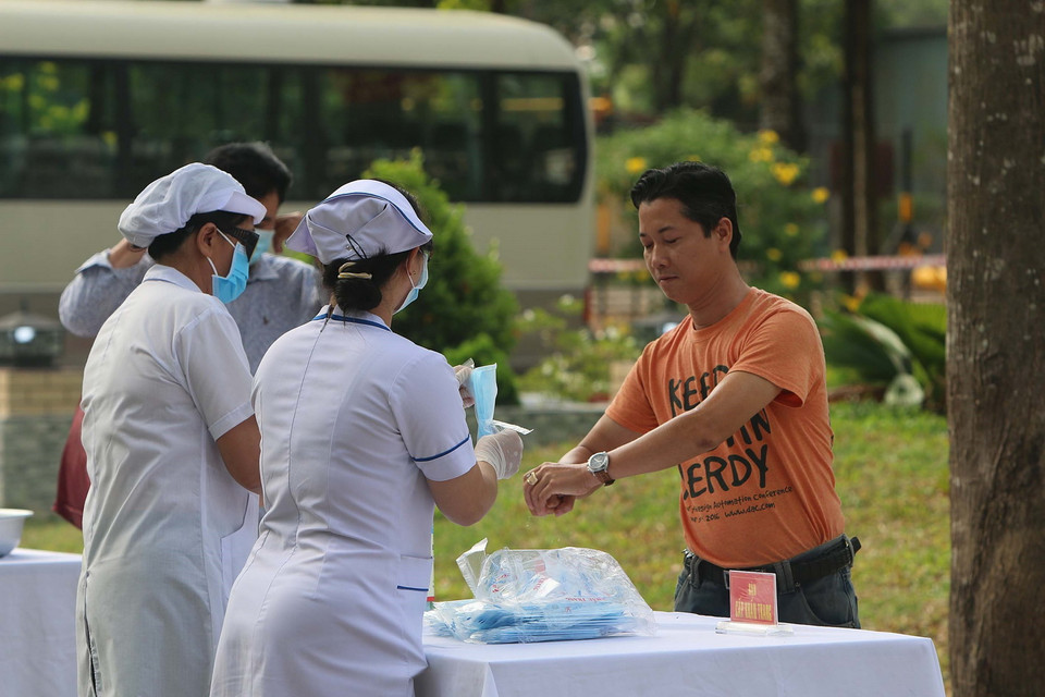 Các công dân đi từ vùng có dịch thực hiện khử trùng lần thứ 2 trước khi vào khu tiếp nhận cách ly tại Sư đoàn 317. (Ảnh: Thanh Vũ/TTXVN)