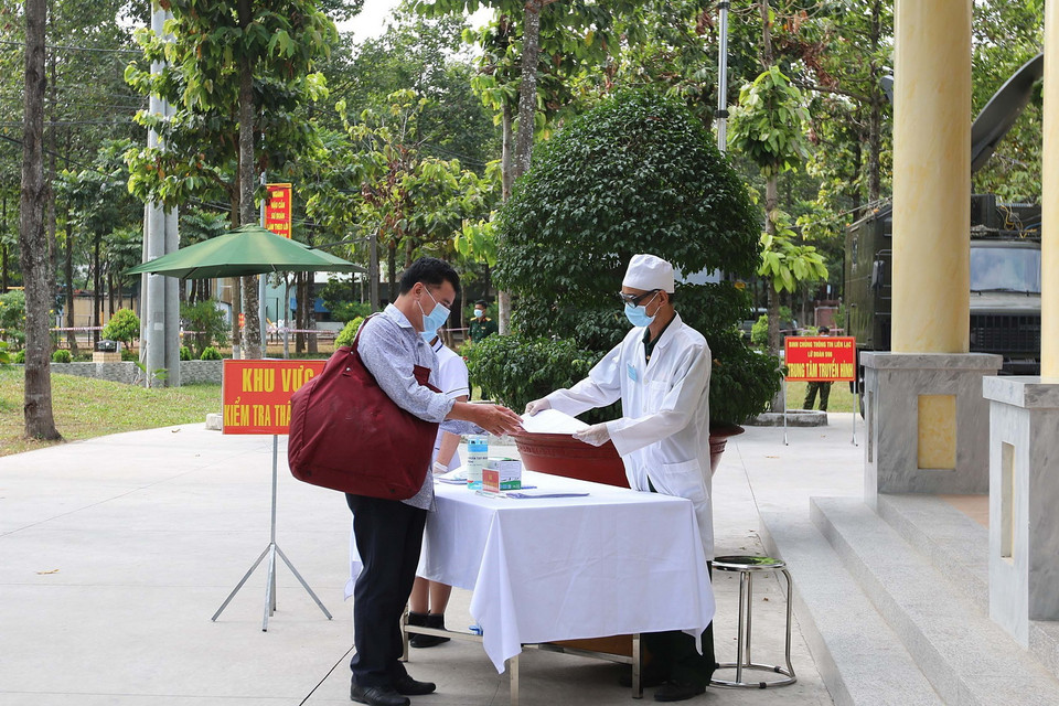 Các công dân đi từ vùng có dịch thực hiện khử trùng lần thứ 2 trước khi vào khu tiếp nhận cách ly tại Sư đoàn 317. (Ảnh: Thanh Vũ/TTXVN)