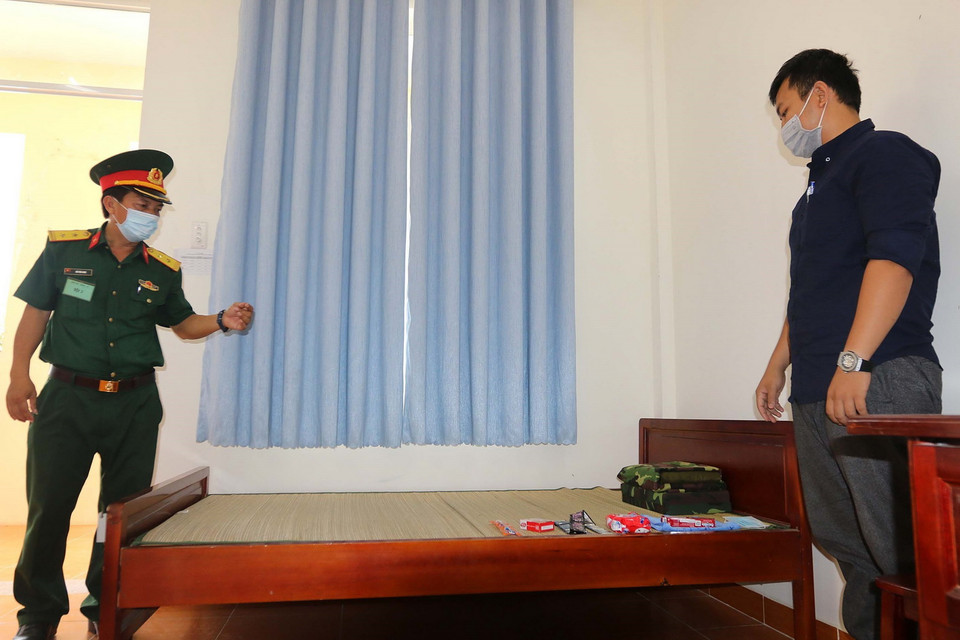 Cán bộ, chiến sỹ Sư đoàn 317 tiếp nhận và hướng dẫn các công dân cách ly về nội quy và cách thức sinh hoạt tại khu cách ly. (Ảnh: Thanh Vũ/TTXVN)