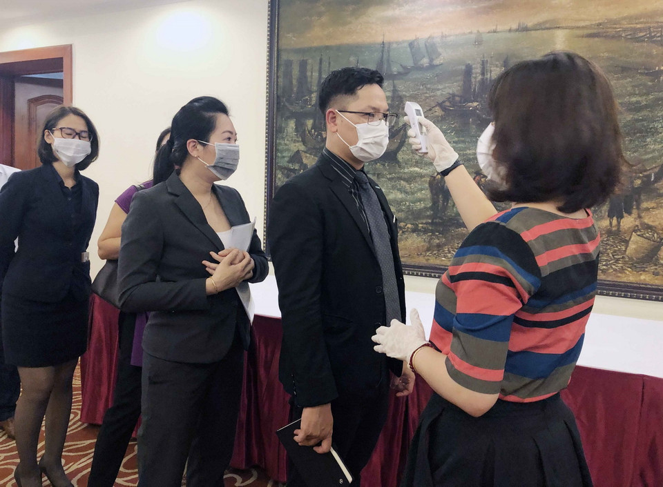 Khách đến dự hội nghị ở TP Hồ Chí Minh được kiểm tra nhiệt độ, rửa tay bằng nước diệt khẩu và phát khẩu trang miễn phí. (Ảnh: Mỹ Phương/TTXVN)