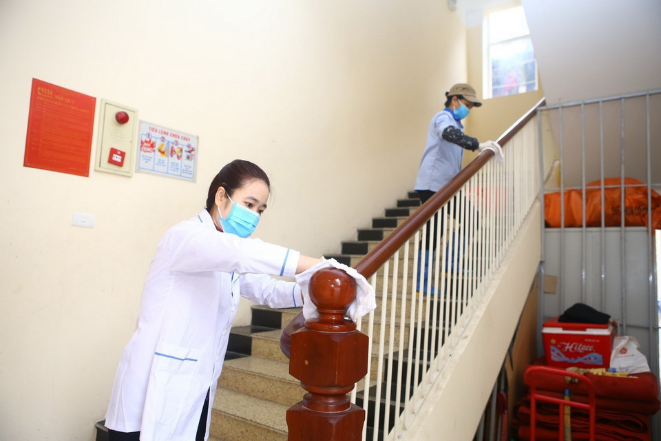 Nhân viên trường THPT Trần Nhân Tông (Hà Nội) lau khử khuẩn bề mặt tại các tay vịn cầu thang. (Ảnh: Minh Quyết/TTXVN)