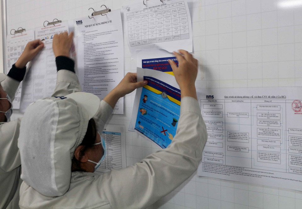 Dán thông tin và cách phòng chống dịch bệnh nCoV tại bản tin của doanh nghiệp cho công nhân theo dõi trong khu công nghiệp ở Hà Nam. (Ảnh: Đại Nghĩa/TTXVN)