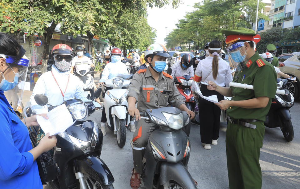 Lực lượng chức năng kiểm tra giấy tờ tùy thân và xác nhận đi làm, ra ngoài của cơ quan với người dân lưu thông trên đường Đào Tấn, Hà Nội, sáng 28/7. (Ảnh: Lâm Khánh/TTXVN)