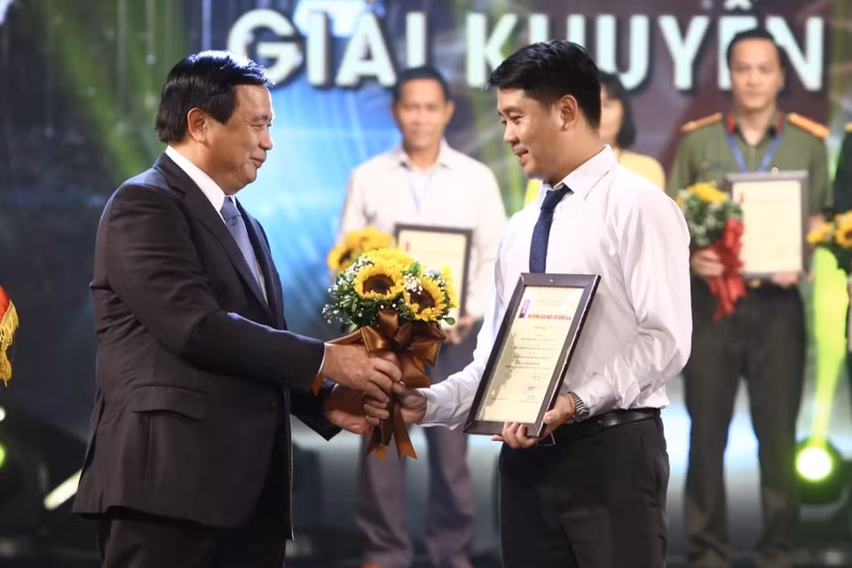 Bí thư Trung ương Đảng, Giám đốc Học viện Chính trị Quốc gia Hồ Chí Minh Nguyễn Xuân Thắng tặng hoa chúc mừng tác giả Dương Văn Giang (Ban Biên tập Ảnh, Liên Chi hội Nhà báo TTXVN) đoạt giải Khuyến khích. (Ảnh: Minh Quyết/TTXVN)