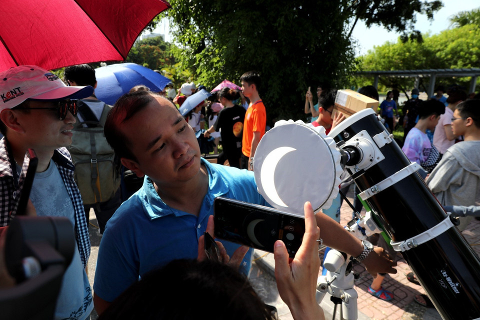 Các bạn trẻ thích thú ghi lại những hình ảnh đáng nhớ của hiện tượng Nhật thực mà 10 năm sau mới có lại tại Việt Nam. (Ảnh: Thành Đạt/TTXVN)