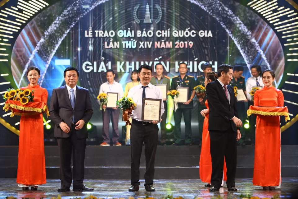 Bí thư Trung ương Đảng, Giám đốc Học viện Chính trị Quốc gia Hồ Chí Minh Nguyễn Xuân Thắng và Ủy viên Trung ương Đảng, Tổng Biên tập báo Nhân Dân, Chủ tịch Hội Nhà báo Việt Nam Thuận Hữu trao Giải Khuyến khích cho tác giả Dương Văn Giang (Ban Biên tập Ảnh, Liên Chi hội Nhà báo TTXVN). (Ảnh: Minh Quyết/TTXVN)
