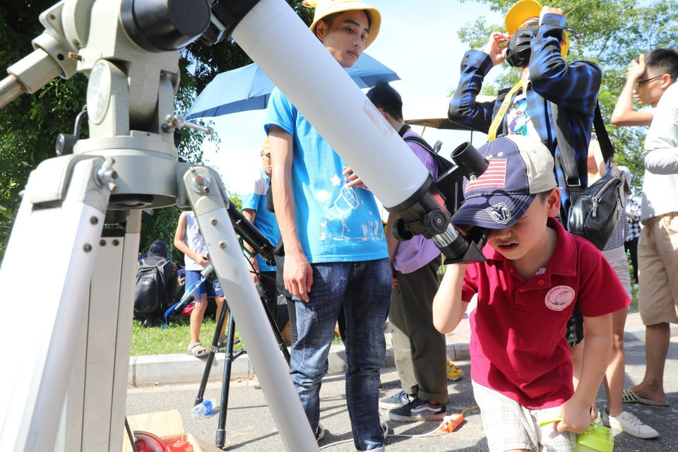 Các em nhỏ thích thú xem hiện tượng Nhật thực qua ống kính thiên văn. (Ảnh: Thành Đạt/TTXVN)