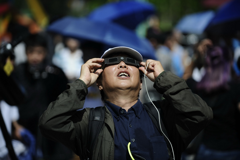 Sử dụng kính chuyên dụng để ngắm hiện thực nhật thực một phần tại công viên Hòa Bình. (Ảnh: Hoàng Việt/TTXVN)