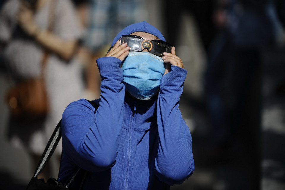 Sử dụng kính chuyên dụng để ngắm hiện thực nhật thực một phần tại công viên Hòa Bình. (Ảnh: Hoàng Việt/TTXVN)