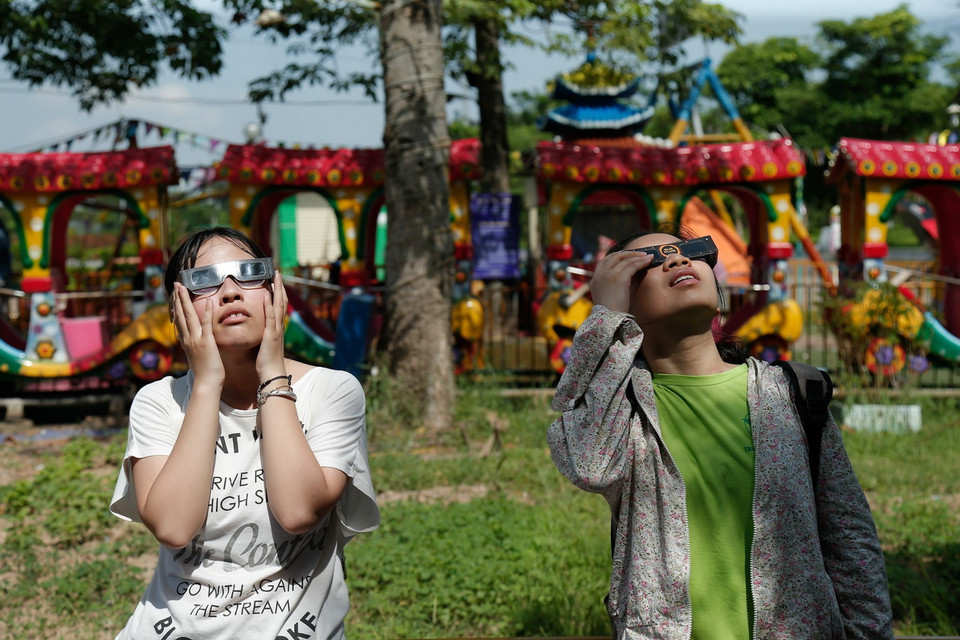 Sử dụng kính chuyên dụng để ngắm hiện thực nhật thực một phần tại công viên Hòa Bình. (Ảnh: Hoàng Việt/TTXVN)