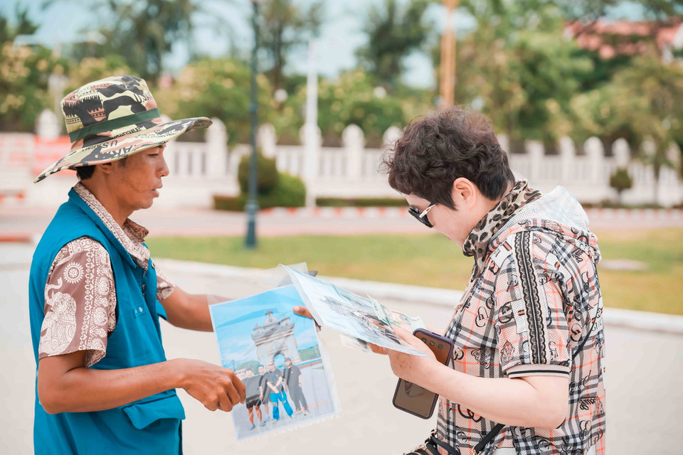 Một du khách nước ngoài đang xem lại những bức ảnh được thợ ảnh chụp tại Patuxai. (Ảnh: Đỗ Bá Thành/Vietnam+)