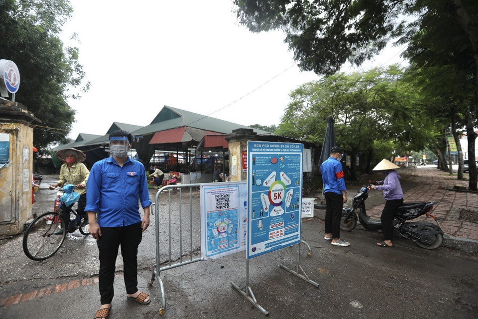  Lực lượng đoàn thanh niên xã Cổ Loa hỗ trợ chốt kiểm tra thẻ ra vào tại khu vực chợ Sa, đảm bảo quy định về phòng, chống dịch COVID-19. (Ảnh: Minh Quyết/TTXVN)