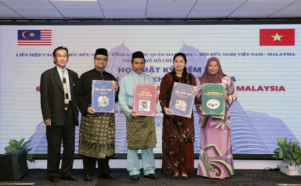 Tổng lãnh sự Wong Chia Chiann và các nhân viên Tổng lãnh sự quán Malaysia tại TP Hồ Chí Minh nhận sách giới thiệu về Tết truyền thống Việt Nam tại buổi họp mặt kỷ niệm lần thứ 65 ngày Quốc khánh Malaysia, ngày 9/9/2022. (Ảnh: Xuân Khu/TTXVN)